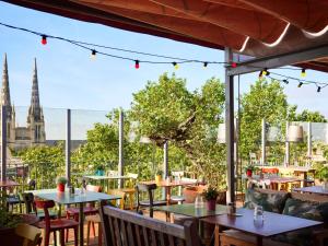 a restaurant with tables and chairs and a view of the spire of a church at Mama Shelter Bordeaux Centre in Bordeaux