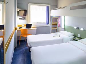 a room with two beds and a desk with a laptop at ibis budget Belem in Belém