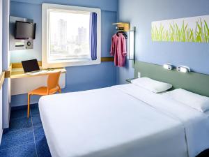 a bedroom with a bed and a desk with a laptop at ibis budget Belem in Belém
