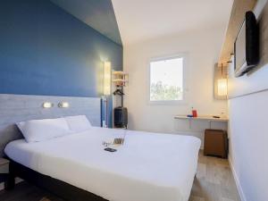 a bedroom with a white bed and a window at Ibis Budget Perpignan Nord Rivesaltes in Rivesaltes