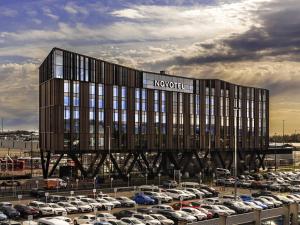 a building with a lot of cars in a parking lot at Novotel Christchurch Airport in Christchurch