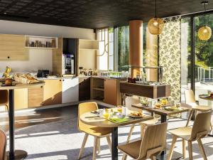 una cucina e una sala da pranzo con tavoli e sedie di Mercure Agen Centre a Agen