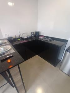 a kitchen with a black counter and a table at Flat LR'Barrotti in Rio Claro