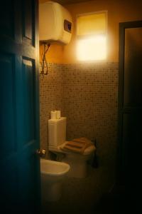 a bathroom with a white toilet and a light at Djabraba's kA Marku e Maria in Vila Nova Sintra