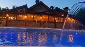 a swimming pool with a fountain in front of a house at Ranč Lipe in Orašje
