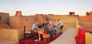 un grupo de personas sentadas en una mesa en el desierto en Maison d'hôte sirwaji, en Assa 29 fotos más