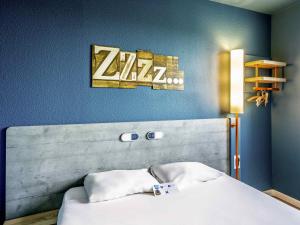 Un dormitorio con una cama y un cartel en la pared. en ibis budget Versailles - Trappes, en Trappes