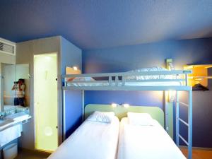 a bedroom with two bunk beds and a mirror at ibis budget Brive La Gaillarde in Brive-la-Gaillarde