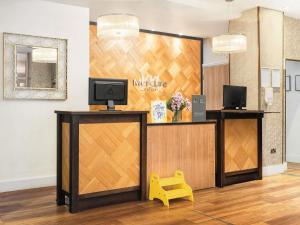 a salon reception with a tv and a yellow stool at Mercure Doncaster Centre Danum Hotel in Doncaster