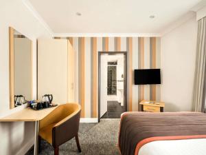 a hotel room with a bed and a desk at Mercure Doncaster Centre Danum Hotel in Doncaster