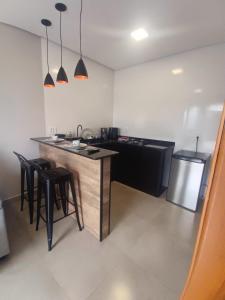 a kitchen with a counter and some stools in a room at Flat LR'Barrotti in Rio Claro
