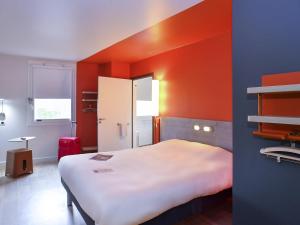 pokój z dużym łóżkiem i pomarańczową ścianą w obiekcie ibis budget Coutances w mieście Coutances