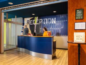 a woman sitting at a reception desk in a scientologist office at Ibis Budget Graz City in Graz