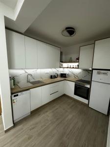 a kitchen with white cabinets and a wooden floor at Apartment Athens 2 in Sombor