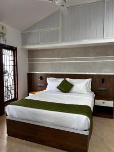 a bedroom with a large bed with a green blanket at The lawrences aqua stay in Cochin