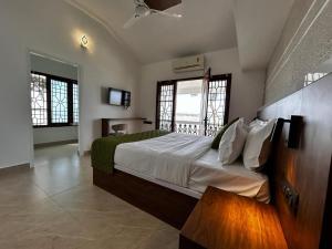 a bedroom with a large bed and two windows at The lawrences aqua stay in Cochin