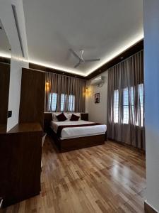 a bedroom with a bed and wooden floors and windows at The lawrences aqua stay in Cochin