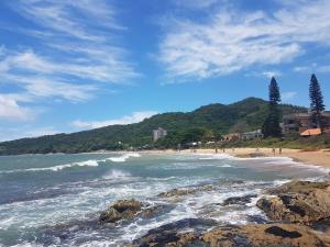 una playa con un grupo de personas en la orilla en Curta Praia de Armação - Casa Orquídea, en Penha