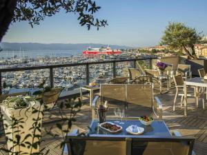 a balcony with tables and chairs and a view of a harbor at Mercure Ajaccio in Ajaccio