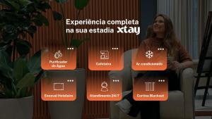 a woman sitting in a chair next to a wall with a diagram at Easy Life Campos PUC by Xtay - Hospede-se próximo ao Viasoft Experience e Estádio Durival in Curitiba