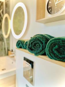 a bathroom with green towels on a shelf and a clock at Le QG des Super Héros Marvel in Nevers