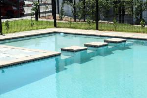 a swimming pool with blue water and steps in it at Willow Villa Apartments, at The Fig in Gaborone