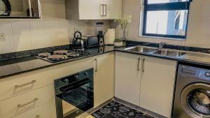 eine Küche mit Herd oberer Ofen neben einer Spüle in der Unterkunft Willow Villa Apartments, at The Fig in Gaborone