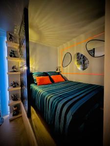 a bedroom with a bed with an orange and blue comforter at Le QG des Super Héros Marvel in Nevers