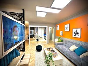a living room with orange walls and a large tv at Le QG des Super Héros Marvel in Nevers