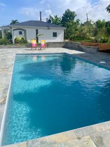 a pool with two chairs in front of a house at Coco-orchidées Le Domaine Mannou in Sainte-Rose