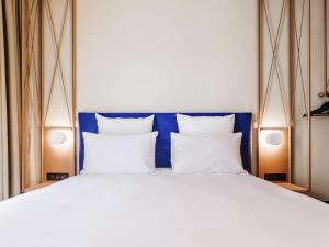 1 cama con almohadas blancas y cabecero azul en Mercure Brest Centre Port, en Brest 41 fotos más