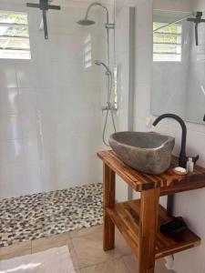 a bathroom with a stone sink on a wooden table at Coco-orchidées Le Domaine Mannou in Sainte-Rose