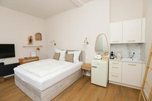 a bedroom with a large white bed and a kitchen at Apartment am Michel mit Parkplatz in Hamburg