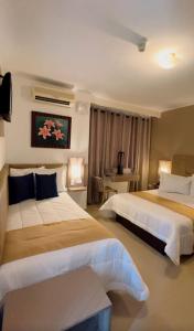 a hotel room with two beds and a table at Hotel Los Lirios in Mérida