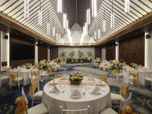 una sala per banchetti con tavoli e sedie bianchi e lampadari di Pullman Lombok Merujani Mandalika Beach Resort a Kuta Lombok Altre 113 foto