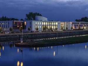 a large white building next to a body of water at Mercure Hotel Schweinfurt Maininsel in Schweinfurt