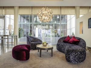 a living room with couches and a table and a chandelier at Mercure Hotel Schweinfurt Maininsel in Schweinfurt