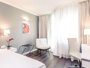 a hotel room with a bed and chairs and a window at Mercure Hotel Raphael Wien in Vienna +74 photos