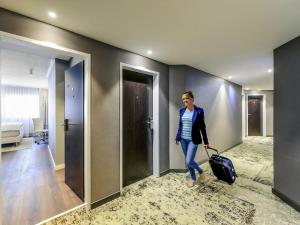a woman is pulling a suitcase in a hotel room at Mercure Hotel Raphael Wien in Vienna