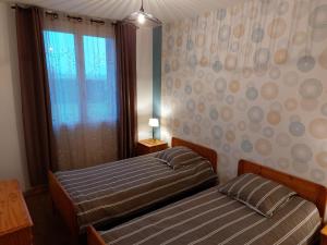 two beds in a small room with a window at gite isolée proche futuroscope Airvault in Saint-Clair +3 photos