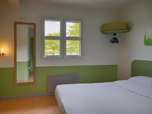 a bedroom with a bed and a mirror and a window at ibis budget Redon in Redon