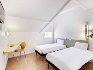una habitación con dos camas y una mesa y una silla en Ibis Budget Agen, en Le Passage 86 fotos más