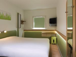 a bedroom with a white bed and a small window at Ibis Budget Sélestat in Sélestat
