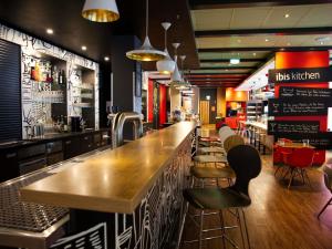 a bar in a restaurant with a wooden counter and stools at ibis Köln Messe in Cologne +62 photos
