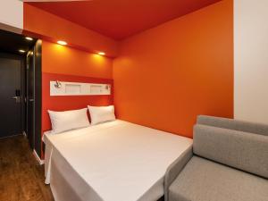 a small bedroom with a white bed and orange walls at ibis budget Recife Jaboatão in Recife