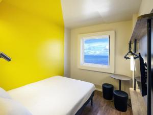 a yellow room with a bed and a window at ibis budget Recife Jaboatão in Recife