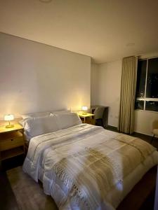 a bedroom with a large white bed with two lamps at Apartamento completo en Sabaneta in Sabaneta