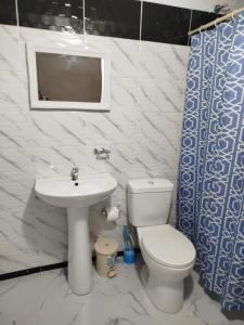 Un baño con inodoro, lavabo y espejo. en Hotel El Almendro, en Pedernales