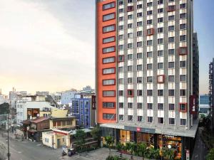 a tall red building in the middle of a city at Ibis Saigon Airport in Ho Chi Minh City