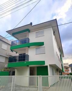 ein weißes und grünes Gebäude mit einem Zaun davor in der Unterkunft Residêncial Campinas a 400 Metros da praia de Palmas in Governador Celso Ramos + 85 Fotos